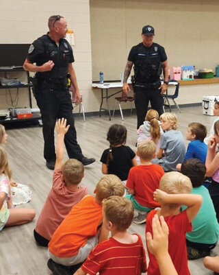 Former Police Chief Scott Pack and Officer Travis Hutzell, SBL’s current liaison officer, answer questions from a group of excited youngsters.