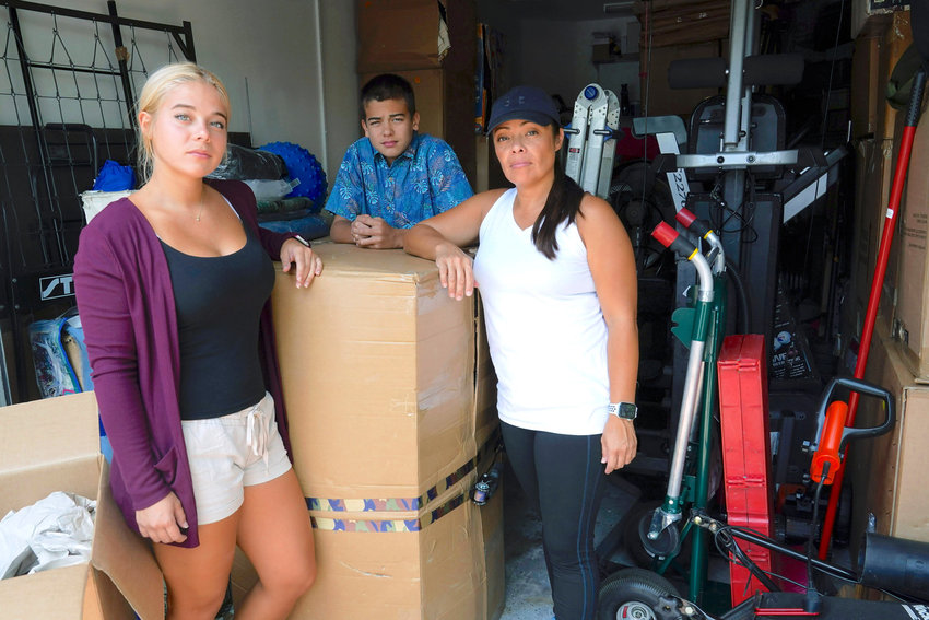 TIGHT SPOT — Wendy Kaufman stands at the entrance to her packed garage with her daughter Jaedyn, 19, and son Julian, 14, Tuesday, April 12, in Doral, Fla. The Kaufman’s moved from Germany and have been unable to find a home big enough that they can afford.