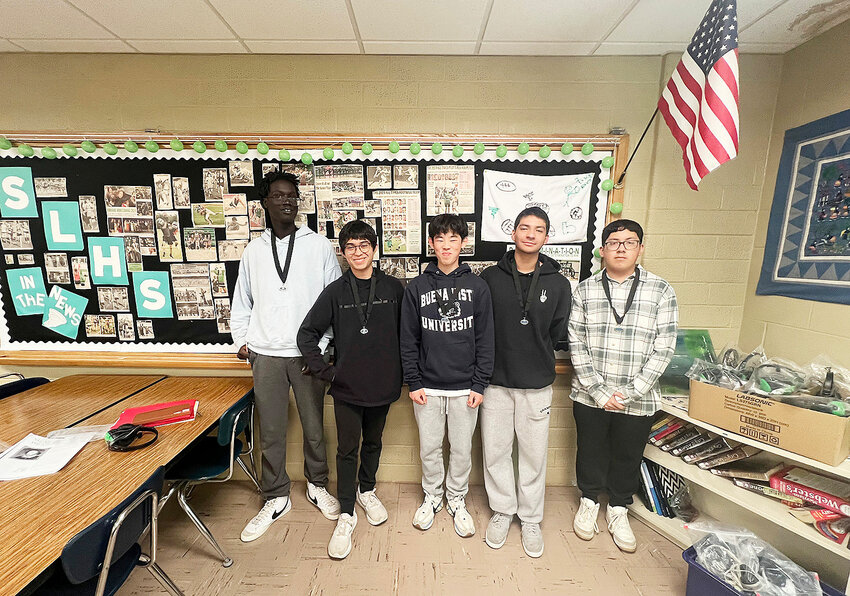 From left: Riak Tut, Eden Laguna-Zavala, John Schwint, Frank Arbizu Guerra and Fernando Ramirez have qualified for the national competition for National History Day. A display of clippings from the Times Pilot forms their backdrop. Newspapers, after all, are the first draft of history.