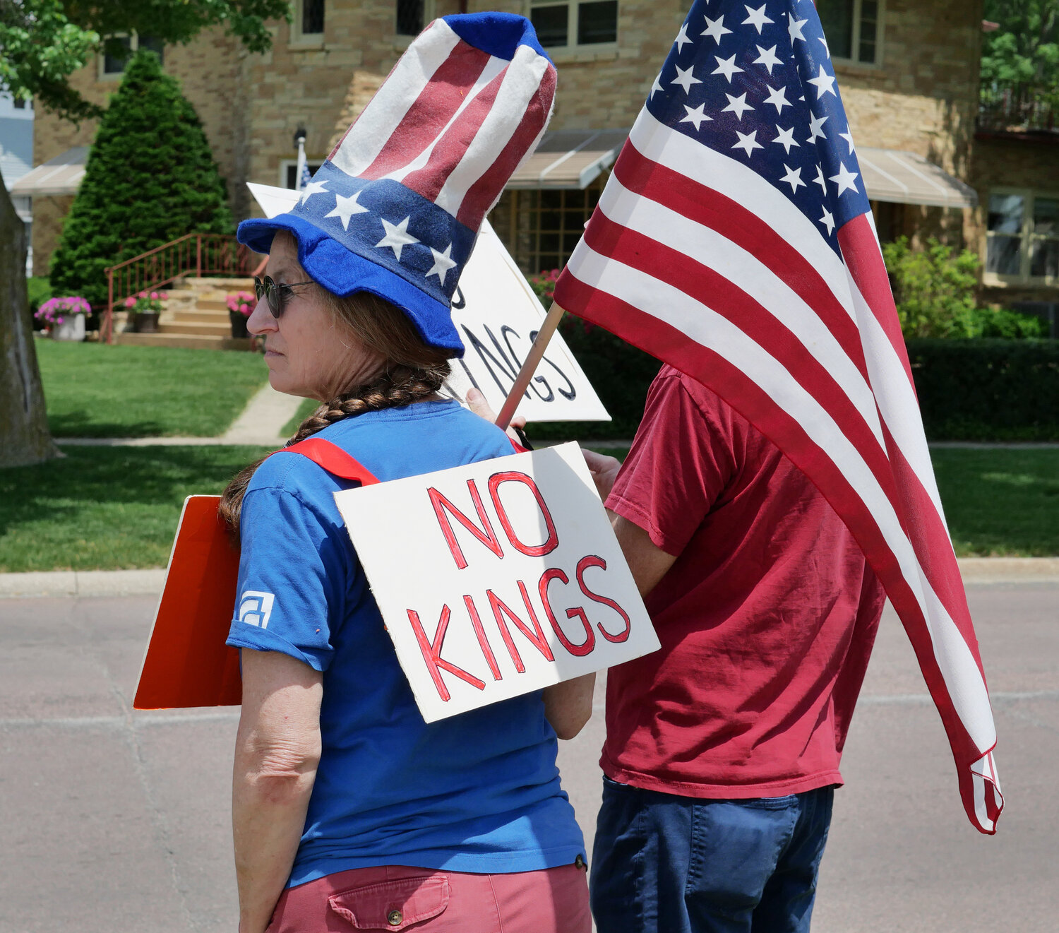 Julie Schmidt of Spencer wears a simple ‘No Kings’ sign with an Uncle Sam-style hat during Saturday’s protest.