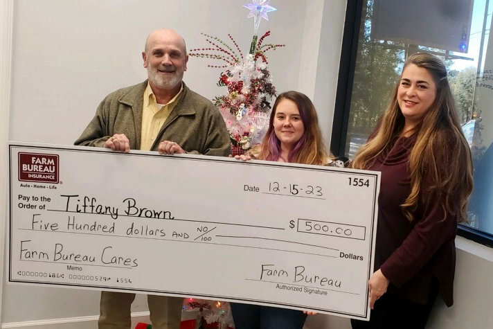 Brown Family: Farm Bureau Insurance Agent Steve Frazier and Secretary Karen Lyons present a $500 Farm Bureau Cares donation to Tiffany Brown.