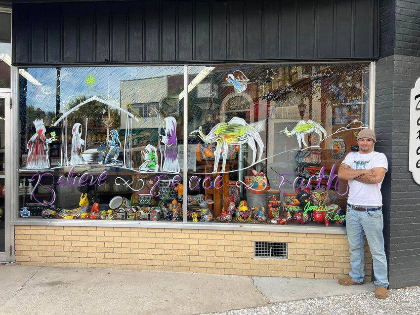 Jonas standing in front of his window artwork that was on display at Dixie Auto Parts on East Washington Street