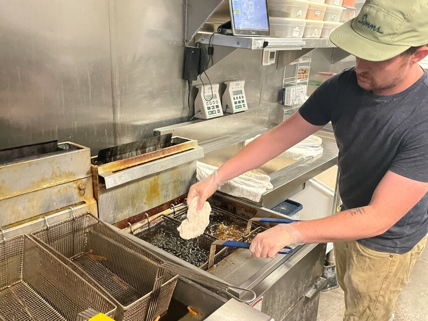 Twist Hot Chicken employee Wyatt Hostetler prepares to drop a fillet in the deep fryer in preparing to make a sandwich at the Peoria restaurant. (Independent Newsmedia/Patrick O’Grady)