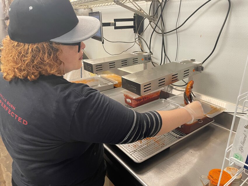 Twist Hot Chicken employee Shavonne Hill dips a cooked chicken fillet into one of the restaurants sauces. (Independent Newsmedia/Patrick O’Grady)