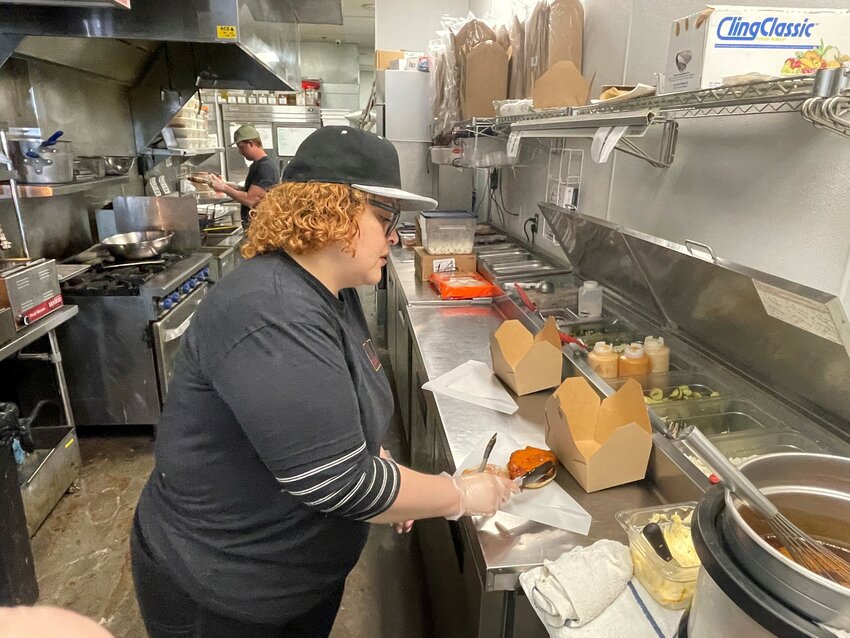 Twist Hot Chicken employee Shavonne Hill preps a sandwich at the Peoria restaurant. (Independent Newsmedia/Patrick O’Grady)