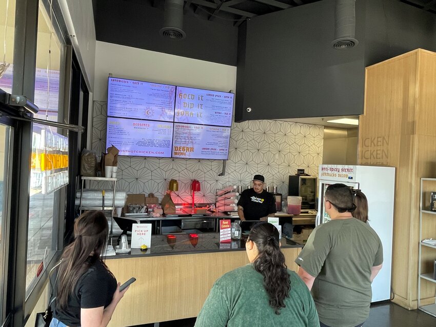 Customers check out the menu at Twist Hot Chicken in Peoria. The restaurant is one of a growing number of Nashville hot chicken sandwich joints that are proliferating around the Valley. (Independent Newsmedia/Patrick O’Grady)
