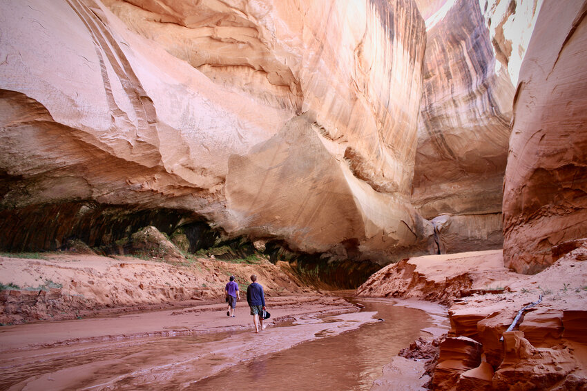 Jack Stauss and filmmaker Ben Masters walk into Cathedral in the Desert on April 10, 2023. At one point, Lake Powell was so high that people could drive boats nearly 100 feet above Cathedral's distinctive waterfall. (Photo by Alex Hager/KUNC)