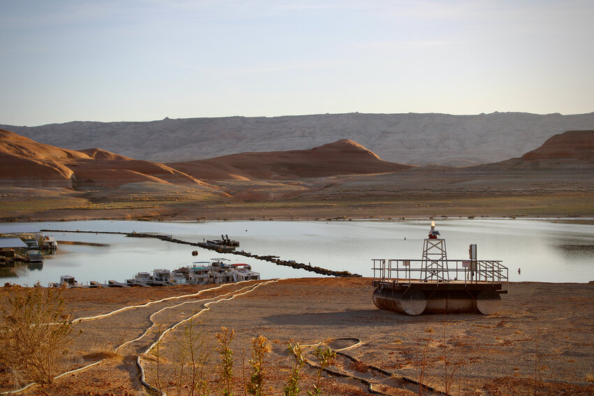 Docks and buoys, once floating atop dozens of feet of water, sit stranded on the sand at Bullfrog Marina on April 9, 2023. Dropping water levels have made it harder to operate marinas and docks that are part of Lake Powell's recreation industry, which attracts millions of people each year. (Photo by Alex Hager/KUNC)