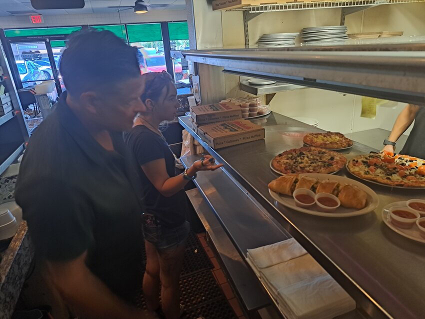 Floridino’s co-owner Shaun Kelley and an employee wait on a dine-in order to be completed by kitchen staff. The Italian restaurant has been trying to keep prices reasonable since it opened in 1996.