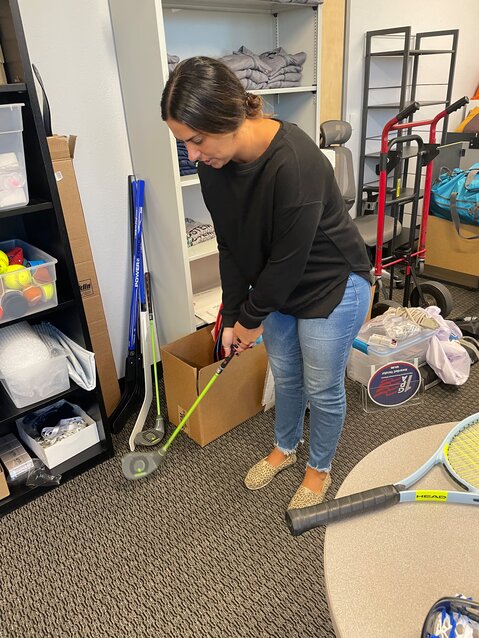 Haley MacLean goofs around with one of the golf clubs used for the class in a storeroom for class equipment. (Independent Newsmedia/Tom Blodgett)