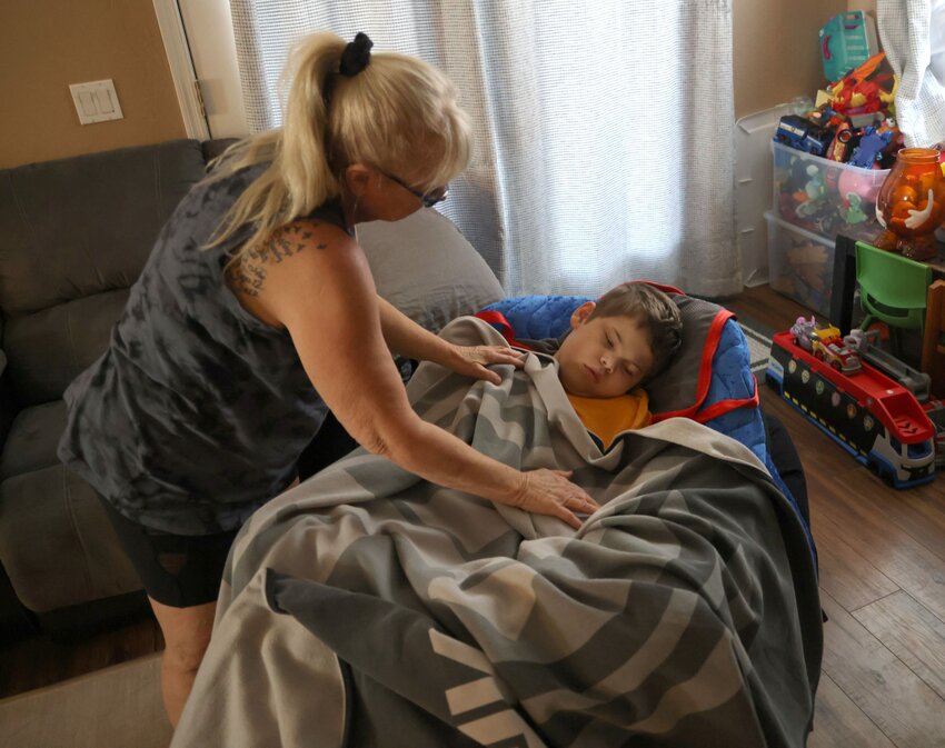 Ronda Barnes, Tyson Coon’s non-familial paid caregiver, covers Tyson with a blanket on Oct. 6, 2023. (Photo by Kevinjonah Paguio/Cronkite News)