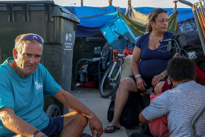 Jay Duval and Melissa Valles sit near their tents on the sidewalk that will soon be cleared by Phoenix officials. Both have lived in this area of The Zone for two years. (Photo by John Leos/Cronkite News)