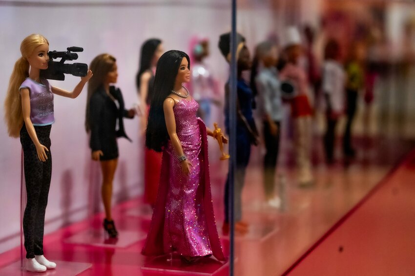 A display case at the “Barbie: A Cultural Icon” exhibition at the Phoenix Art Museum shows off some of the many career Barbies, including a camerawoman Barbie and an award-winning actress Barbie. Throughout her existence, Barbie has taken on more than 250 different careers. Photo taken in Phoenix on Feb. 21, 2024. (Photo by Emily Mai/Cronkite News)