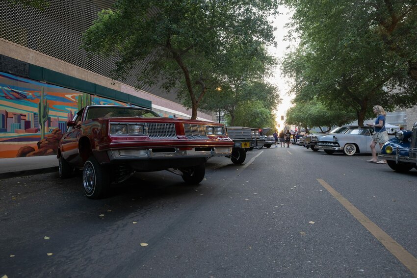 People in downtown Phoenix admire lowrider cars from bygone eras during the second Saturday of the month car show on April 13, 2024. (Photo by David Ulloa Jr./Cronkite News)
