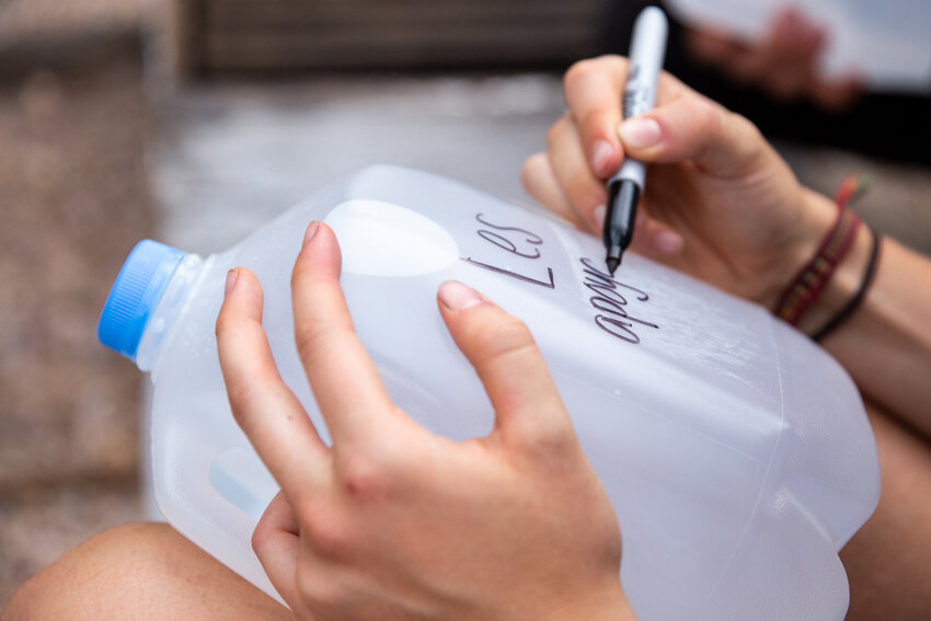 Vanessa Savel writes “We support you”on a gallon of water left for migrants. Other messages that volunteers write in Spanish on water bottles bottles include “Good luck” and “Go with the force of God.” (File photo by Ellen O’Brien/Cronkite News)