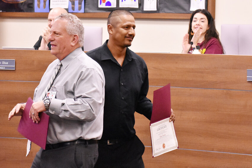 Ulysses Uranda, lead custodian at Perry High School, smiles and shows off a certificate as he walks behind Chandler Unified School District Superintendent Frank Narducci during a Hispanic Heritage Month event. 