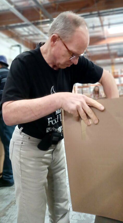 A resident packs a food box during Everlasting’s weekly volunteer trip to St. Mary’s Food Bank in Phoenix.