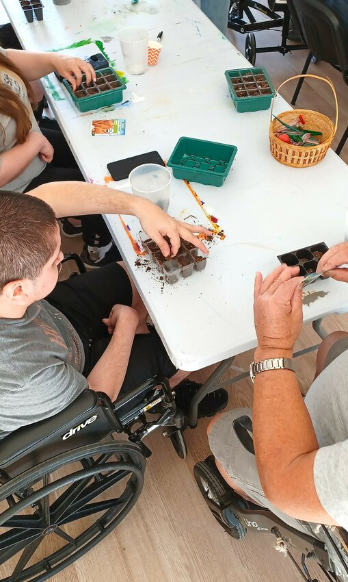 Residents plant seeds to add to the facility’s culinary gardens.
