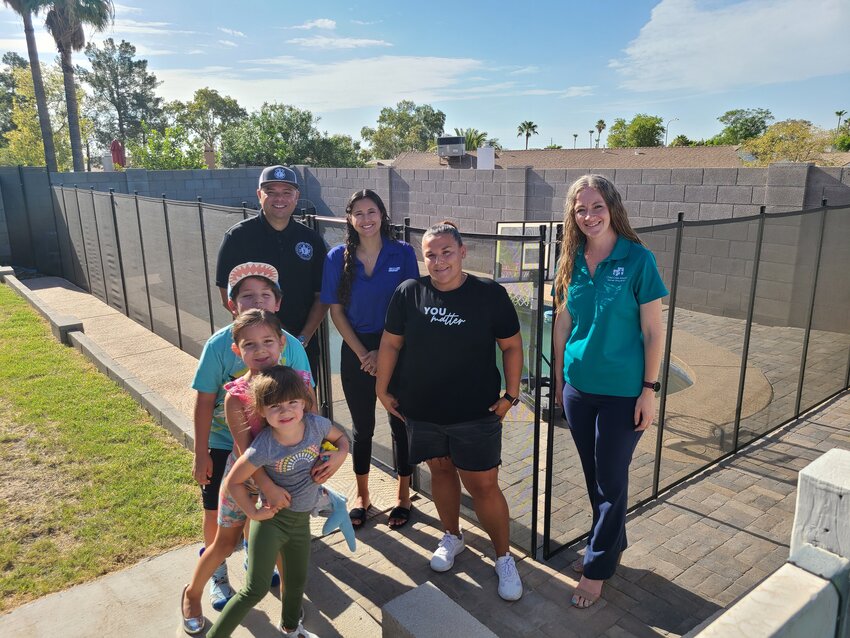 The Stoll family in front of their new pool fence with team members from Child Crisis Arizona, SRP, and United Phoenix Firefighters Charities.