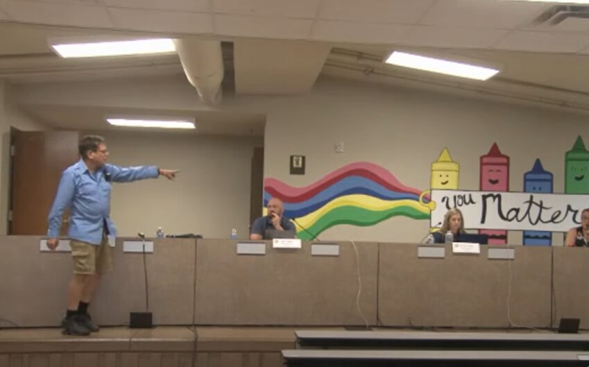 Jeremy Hoenack (left) points as he storms out of the schoolboard meeting.