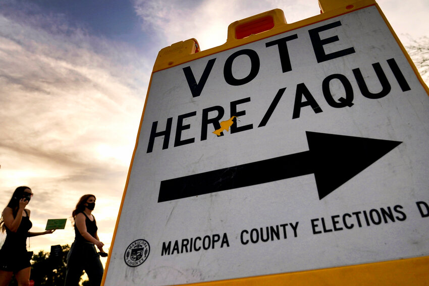 Voters deliver their ballot to a polling station in Tempe on Nov. 3, 2020. (The Associated Press/Matt York)