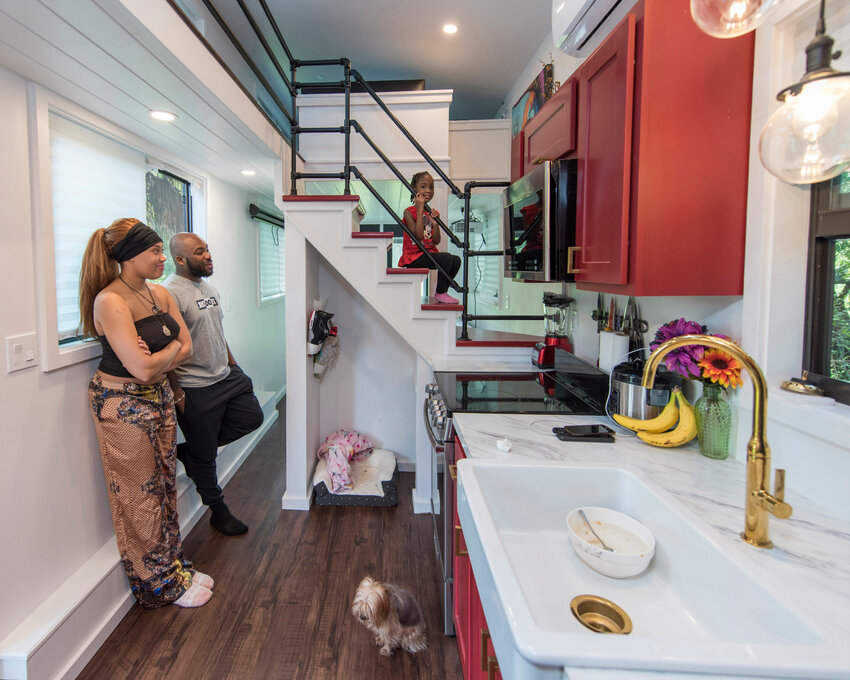 Air Force Staff Sgt. Kevin Inniss and his wife, Shanice, along with their dog Quincy, watch as their daughter, Urie, sits proudly on the stairs of the family's newly-constructed Tiny Home. The Inniss family received a grant courtesy of Operation Tiny Home, a national non-profit organization in partnership with Sutter Home Family Vineyards, to build 400-square-feet of living space to call their own. (U.S. Air Force photo by Matthew S. Jurgens)