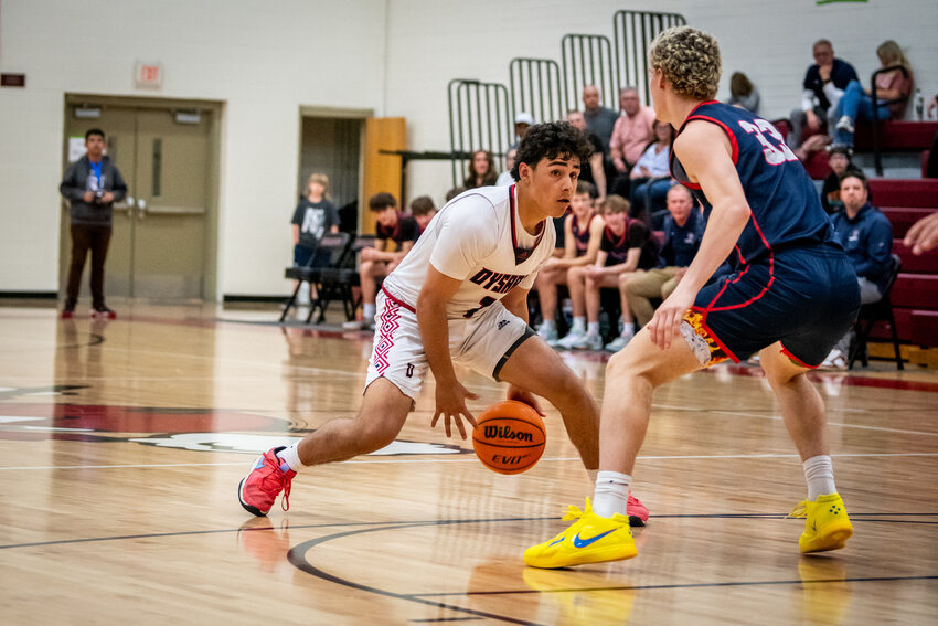 Dysart senior point guard Nate Morales crosses over ALA-Queen Creek junior forward Kingston McCabe during a Feb. 21 first round basketball game at Dysart.