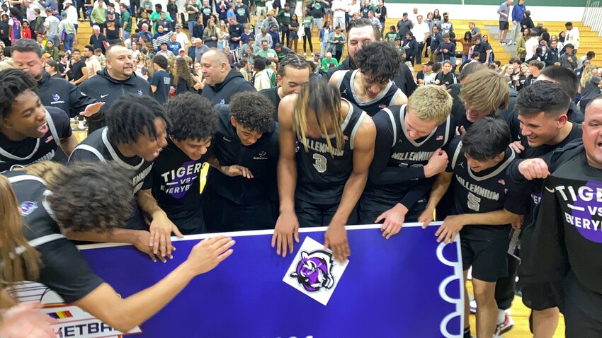 Millennium sophomore Cameron Holmes slaps the Tigers logo on the oversized ticket that the team earned by beating Sunnyslope in the Open Division quarterfinal Feb. 23 to qualify for the Final Four.