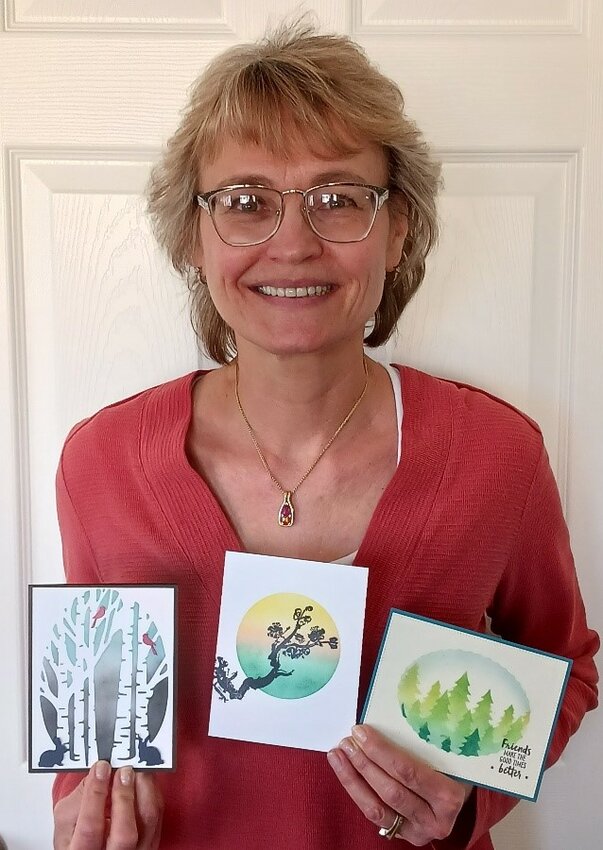Christina Hecht holds samples of the cards she created using the blended ink and stencil technique.