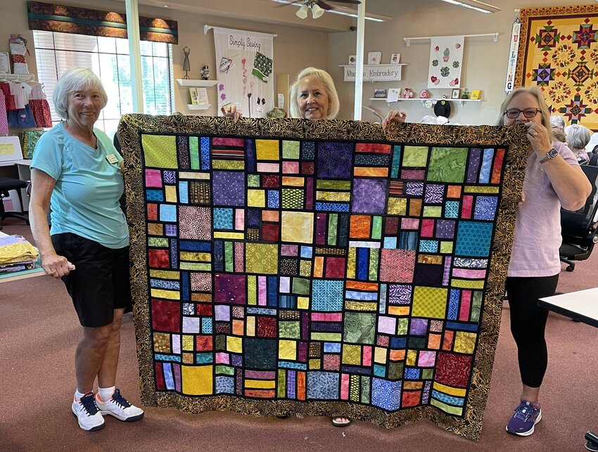 Members of the Cactus Needle Quilters Club show off a piece of work that will be part of the Caring Quilts show at The Grand on March 16.