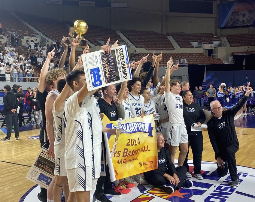 Deer Valley boys basketball players and coaches hold up the 4A Conference trophy and banner after the Skyhawks defeated Tucson Sahuaro 63-31 in overtime to win the program's first state title.
