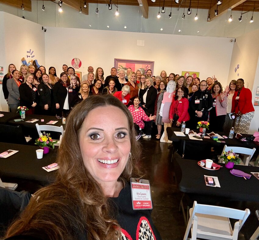 City of Surprise Economic Development Coordinator Kris Cassens takes a selfie with a group of Galentine's Day event attendees in the background.