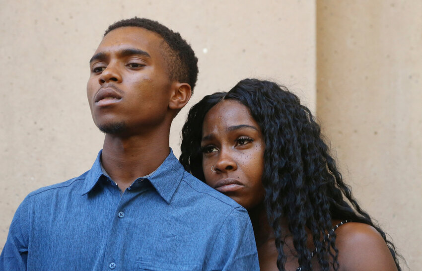 In this June 17, 2019, photo, Dravon Ames, left, and Iesha Harper pause as they listen to a question during a news conference at City Hall in Phoenix. Ames and Harper were cursed at and threatened by Phoenix police in 2019 after their 4-year-old daughter carried a fashion doll out of a dollar store without paying for it. The couple said they were unaware that their young child took the doll. Officers aimed guns at the Black couple during the confrontation, which was captured on video cell phone. (The Associated Press/Ross D. Franklin)