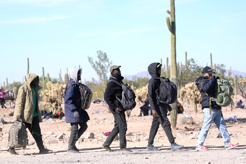 A group of migrants walk to a van as hundreds of migrants gather along the border Tuesday, Dec. 5, 2023, in Lukeville, Ariz. Arizona Republicans in the Legislature are piecing together a ballot proposal that would allow local law enforcement to enforce immigration laws. (Associated Press/Ross D. Franklin)