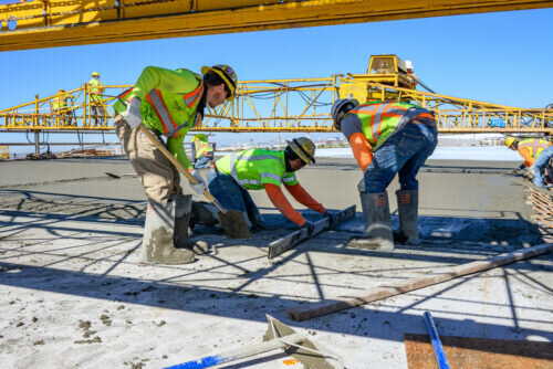 Crews smooth the edges of freshly poured concrete for a ramp as part of the Broadway Curve improvement project.