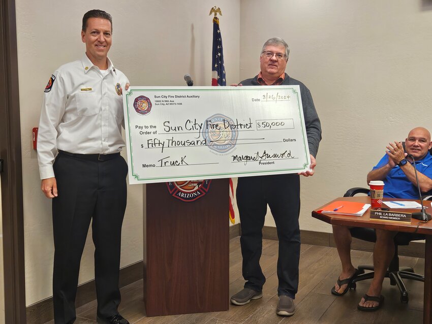 Sun City Fire District Acting Chief Rob Schmitz accepts a $50,000 donation from Mike Bauschka, board member and treasurer of the SCFD Auxiliary.