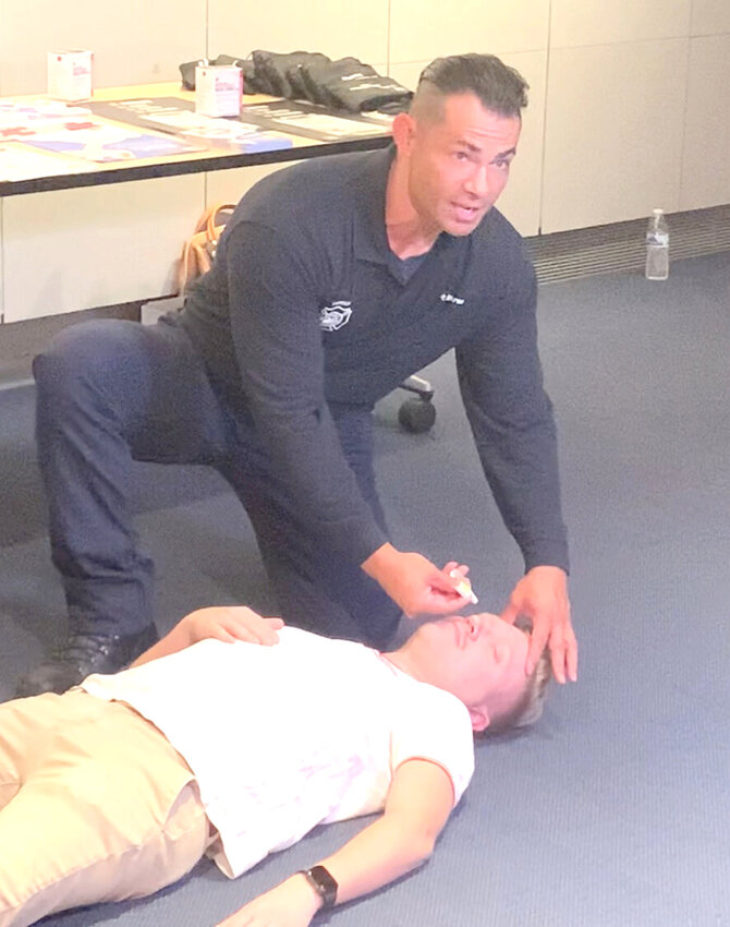 A Phoenix firefighter demonstrates how to administer the overdose-reversal nasal spray naloxone during a media event Monday, Aug. 14, 2023, at Burton Barr Central Library in Phoenix. (Independent Newsmedia/Mark Carlisle)