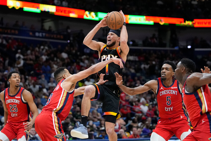 Phoenix Suns guard Devin Booker (1) goes to the basket between New Orleans Pelicans guard CJ McCollum (3) and forward Herbert Jones (5) in the second half of an NBA basketball game in New Orleans, Monday, April 1, 2024. The Suns won 124-111.