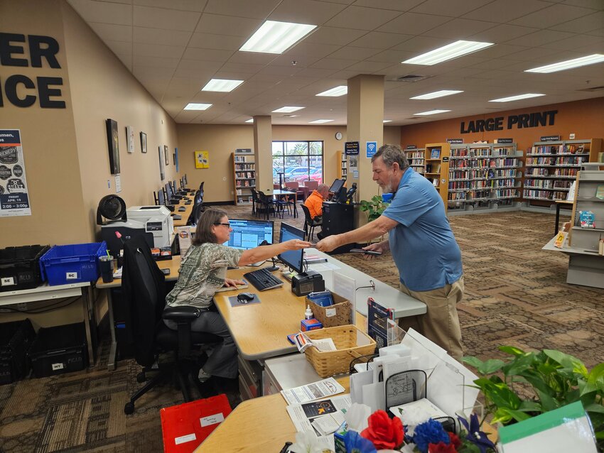 Renada Aung Khin, librarian, checks out a book to Jim Miner at the Fairway Public Library April 8.