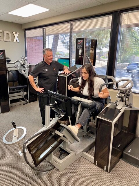 Analisa Gettler is on the machine while Armando Romano, a rehabilitation specialist for the The Center for Total Back Care in Mesa, supervises the process.