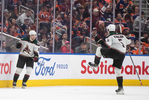 Arizona Coyotes' Matias Maccelli (63) and Michael Kesselring (5) celebrate a goal against the Edmonton Oilers during overtime in an NHL hockey game Friday, April 12, 2024, in Edmonton, Alberta. (Jason Franson/The Canadian Press via AP)