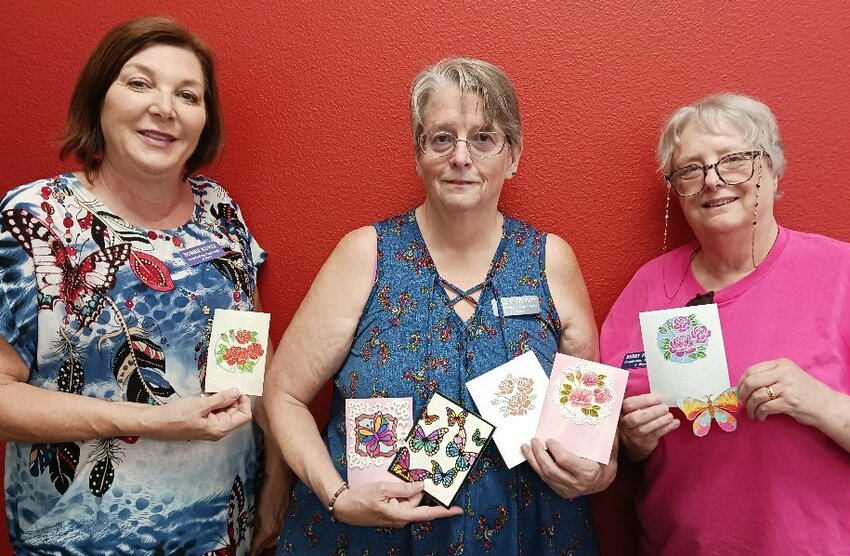 Bobbi Patterson, center, and SPAM members Bobbie Kunze and Debby Floeder display the colorful, glittering cards they created in class.