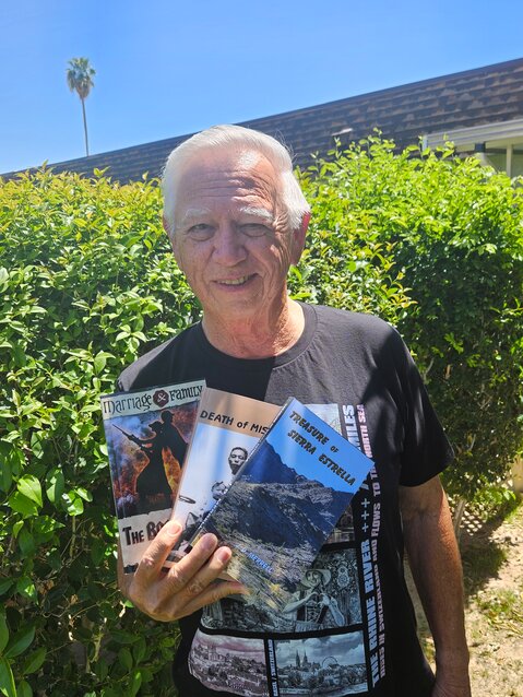Joe Merrell displays his three books outside his Sun City home April 17.
