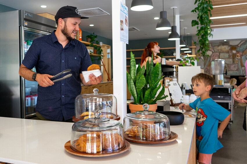 Awaken Cafe Manager Michael Roth serves a cookie to a boy. The coffee shop&rsquo;s primary demographic is families with young children as three schools are nearby.