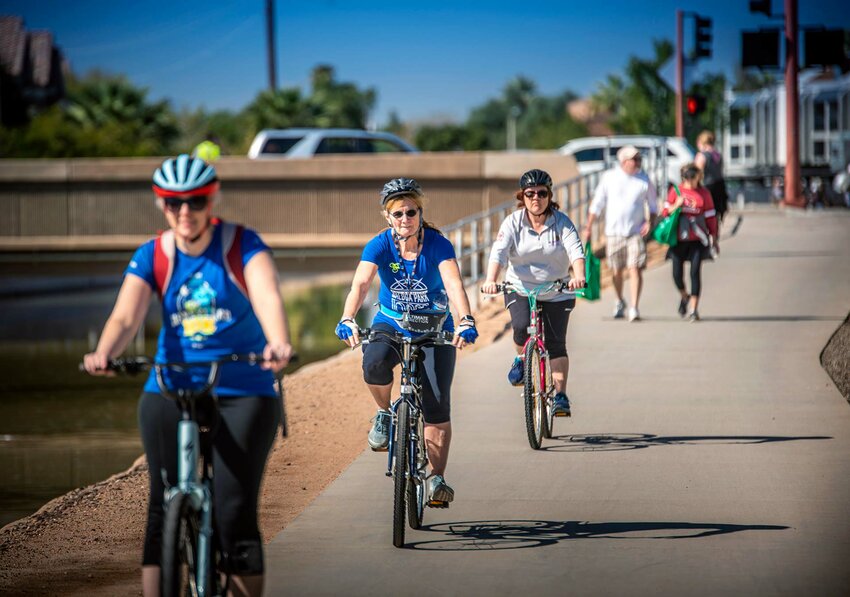 Bicyclists pedal along the Grand Canal in Phoenix, with a vehicle and pedestrian bridge over the canal shown in the background. The city of Phoenix is applying for a $20 million federal grant to replace a bridge over Grand Canal at Van Buren and 40th streets. (Courtesy city of Phoenix)