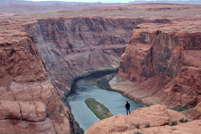 A man looks out over the Colorado River near Page, Arizona on Nov. 2, 2022. The seven states that manage the river are divided about how to account for the impacts of climate change in new plans about sharing its water. (Photo by Alex Hager/KUNC)