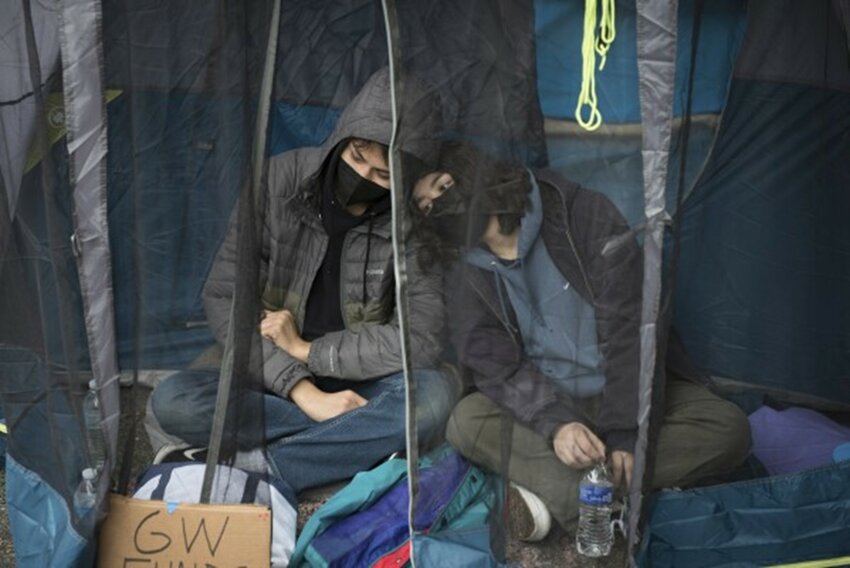 Students protesting the Israel-Hamas war at George Washington University sit in a tent Saturday, April 27, to avoid the rain.