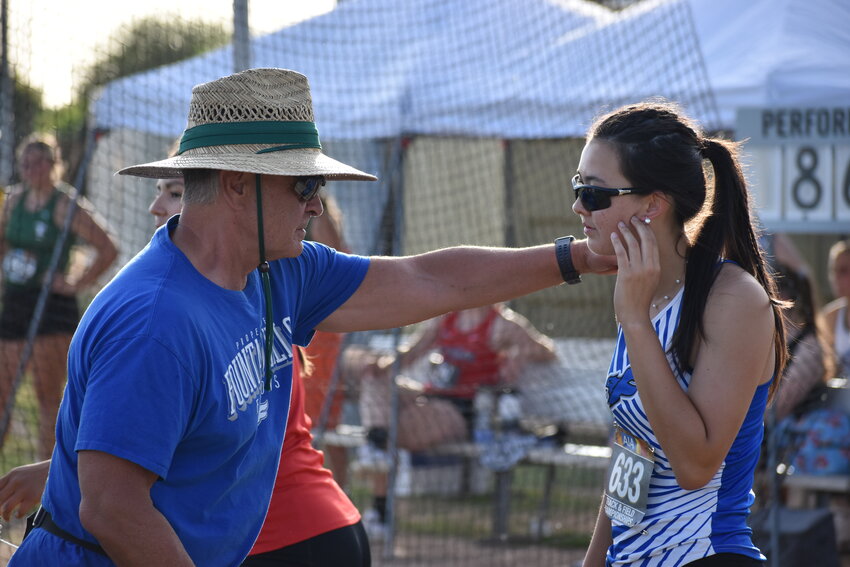 Assistant coach Ed Tafoya gives junior Katie Hampton tips between rounds of her divisional discus competition. (Independent Newsmedia/George Zeliff)
