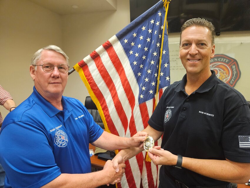 Tim Wilmes, president of the Sun City Fire District board of directors, presents Rob Schmitz with the fire chief&rsquo;s badge May 7 following a special session of the board.