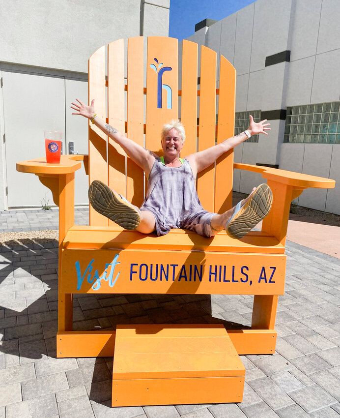 The community is invited to stop by the Fountain Hills Chamber of Commerce to enjoy its new giant Adirondack chair. Pictured is Julie Jones in the chair.